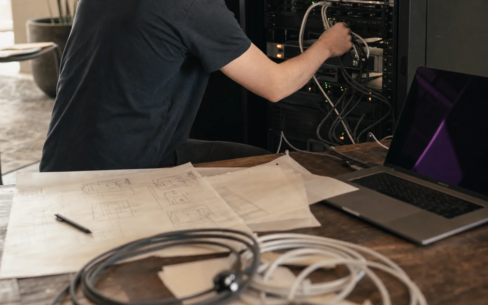 Profissional conectando infraestrutura de servidores entre diagramas e equipamentos de tecnologia