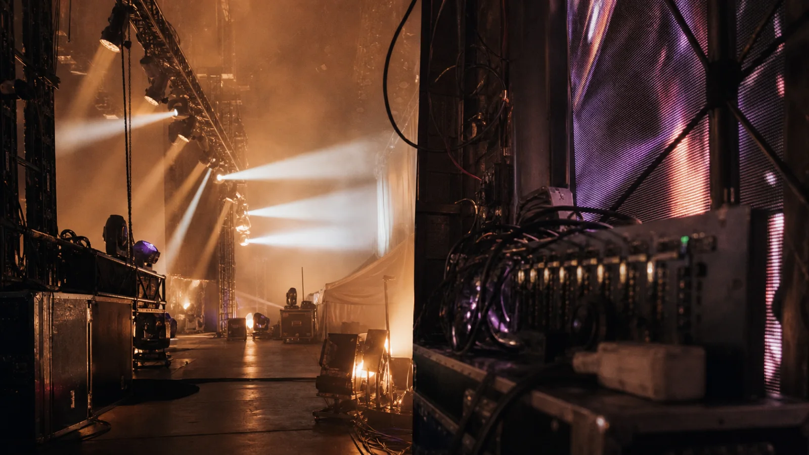 Bastidores de palco com refletores, estruturas, cabos e painel de LED em operação